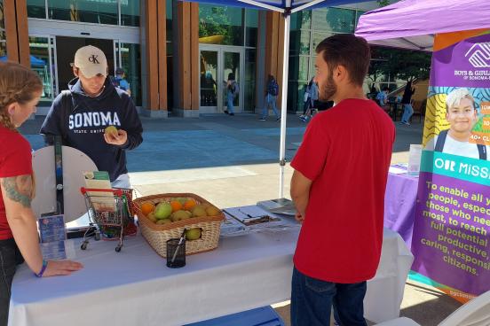 Student picking up fruit at Boys & Girls Club table