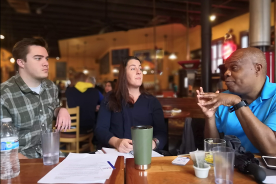 Members of the community are pictured engaged in conversation over tea and coffee. 