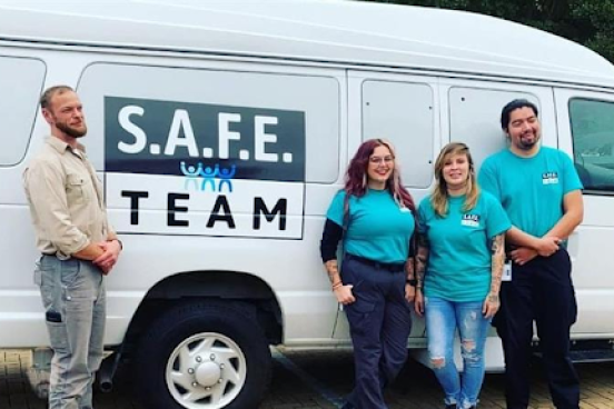 4 people posing outside in front of the SAFE Van