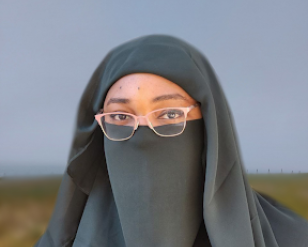 Ashley wearing pink glasses and a green niqab