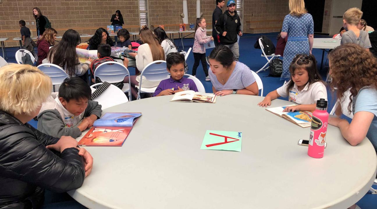 College students read to elementary school students around a table