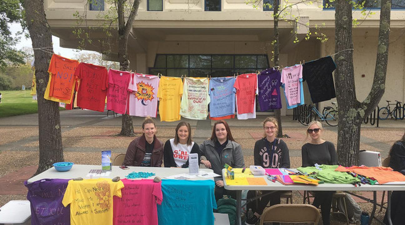 Volunteers sitting behind a table at the event displaying all the shirts made