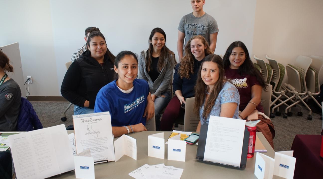 Classmates at the Post-Fire Service & Internship Fair posing for a photo at a table