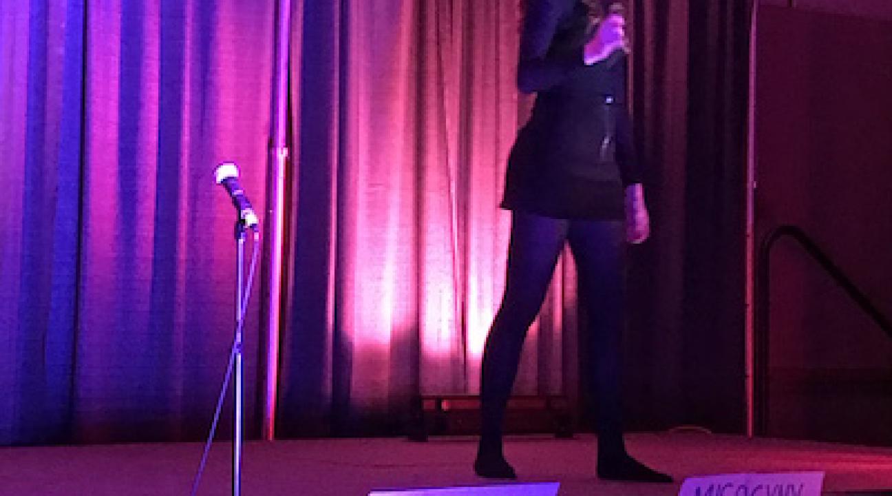 Maddie on stage performing with purple lighting and a black backdrop