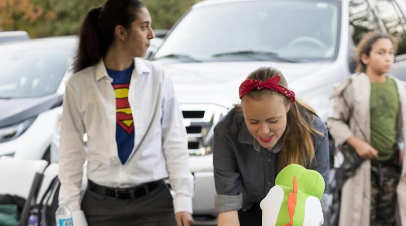 Maddie dressed as Rosie the Riviter handing candy to children