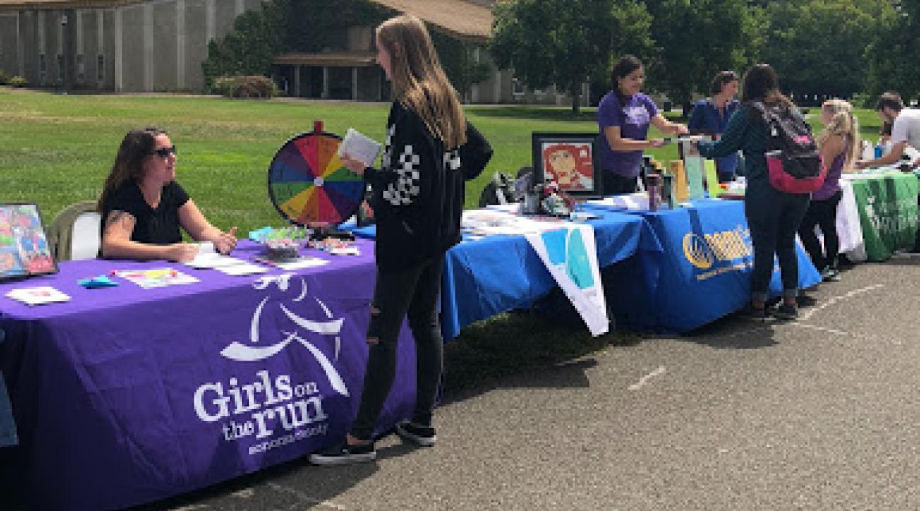 A row of tables with posters outside and people attending them