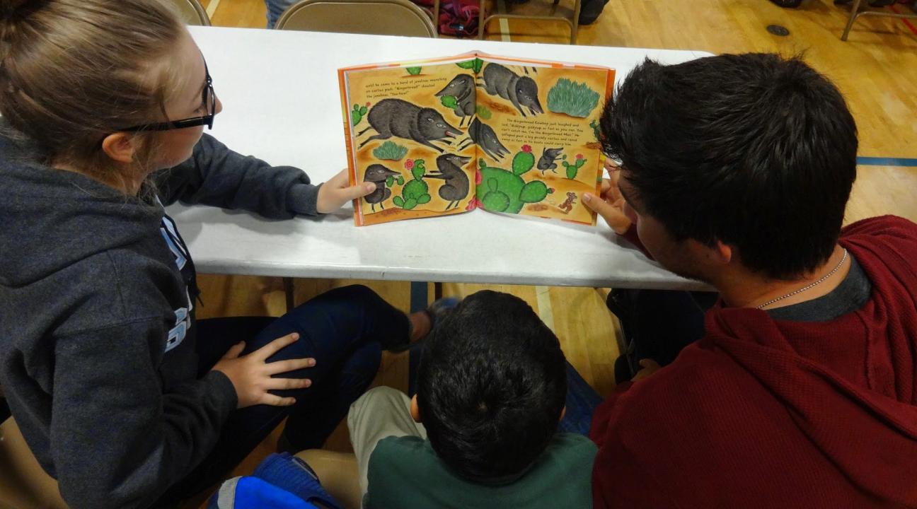 Two SSU students and a Luther Burbank student enjoy a book together.