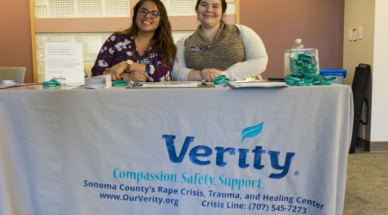 Two women from Verity sit at a presentation table during the internship fair