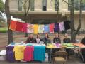Volunteers sitting behind a table at the event displaying all the shirts made