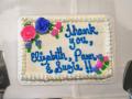 White cake with blue letters that read "Thank you Elizabeth, Pam, and Suzie