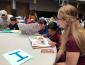 Elementary school students read to college students around a table
