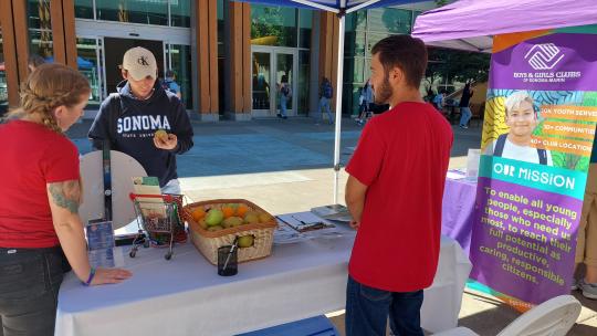 Student picking up fruit at Boys & Girls Club table