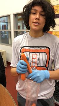 Jasmin holding a carrot while working for the food bank