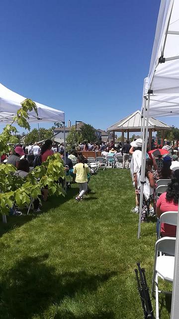 the lawn and crowd underneath popup tents during the memorial