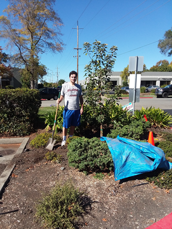 A Student standing with a shovel in a garden