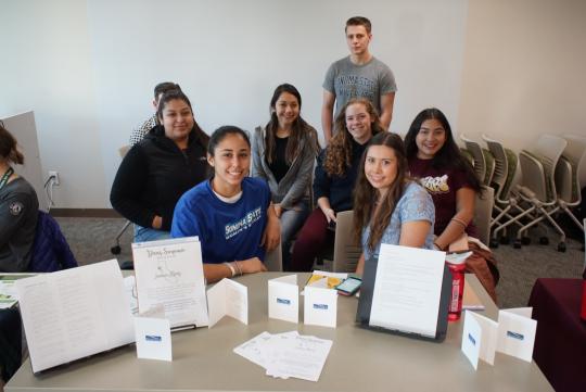 Classmates at the Post-Fire Service & Internship Fair posing for a photo at a table