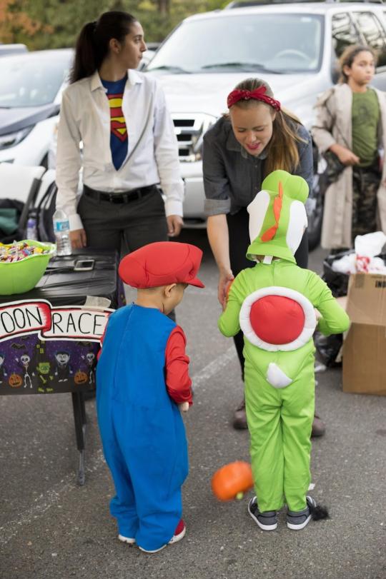 Maddie dressed as Rosie the Riviter handing candy to children