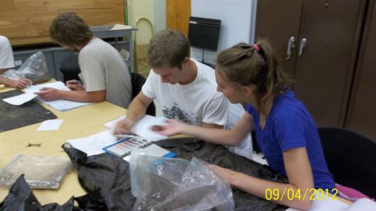 From left to right: Brian Woodward, Stephen Garibaldi, and Caitlyn Yates studying dirt samples in the classroom.